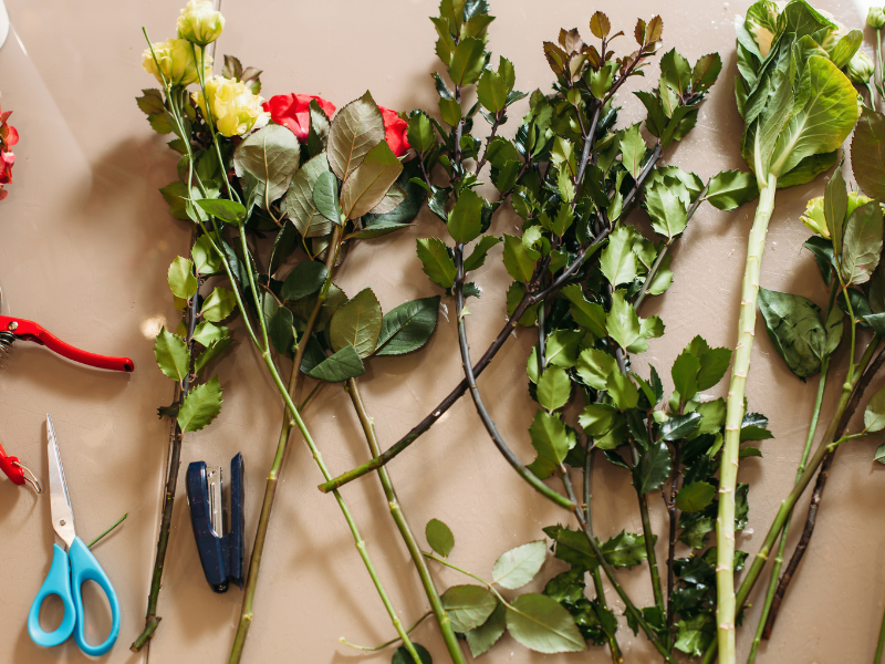 various flower stems and greenery with floral tools 